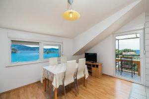 a dining room with a table and chairs and windows at Apartments Fran in Vela Luka