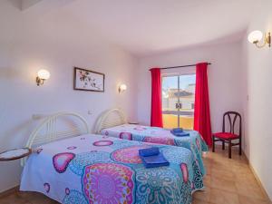 a bedroom with two beds and a window with red curtains at Villa Flor de Maio by Interhome in Patroves