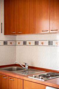 uma cozinha com um lavatório e armários de madeira em Hotel R em Utjeha