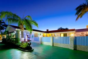 a house with a fence and palm trees at night at Cara Motel in Maryborough