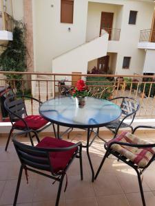 a glass table with chairs and a vase of flowers on a balcony at Casa Louli in Syvota