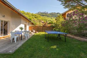 a patio with tables and chairs on the grass at Sous le soleil de Lanfon - Maison au Calme avec jardin clos, LLA Selections by Location Lac Annecy in La Pirraz