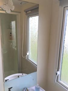 a bathroom with a mirror and a sink and a window at Revamped & Upgraded 6 Berth Static Caravan on Southview Skegness in Skegness