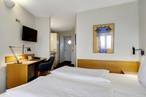 a hotel room with a white bed and a desk at Hotel Garni in Svendborg