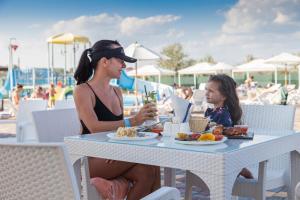 a woman and a little girl sitting at a table with food at Hotel Promenad in Zatoka