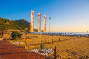 una playa con banderas y sombrillas en la playa en Kahya Hotel, en Alanya