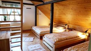 two beds in a room with wooden walls at Chata U Zmrzlyho in Vrchlabí