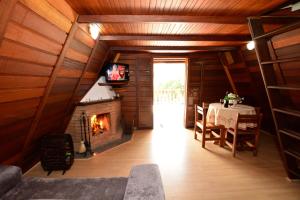 a room with a fireplace and a table and a television at Chalés dos Alpes in Monte Verde
