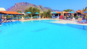 a large swimming pool with a mountain in the background at Zorbas Beach Village Hotel in Stavros