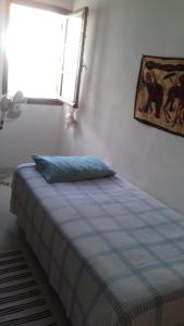 a bed with a blue pillow in a room with a window at Dar el Baraka in Bizerte
