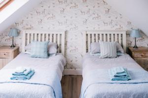 two beds in a room with a wall with deer wallpaper at La Maison de Campagne in Kilmuir