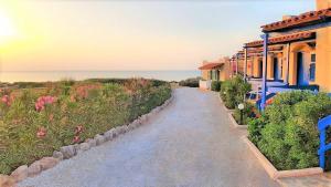 a pathway to a house with the ocean in the background at Zorbas Beach Village Hotel in Stavros