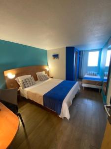 een slaapkamer met een groot bed met blauwe muren bij Hôtel De La Plage in Calais