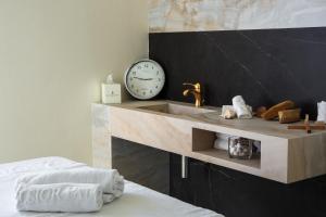 a bathroom with a sink and a clock on a wall at Excelsior Palace Portofino Coast in Rapallo
