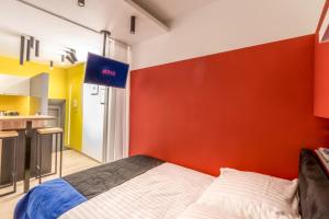 a bedroom with a red accent wall and a bed at Apartment KOBRO - new city center of Lodz in Łódź