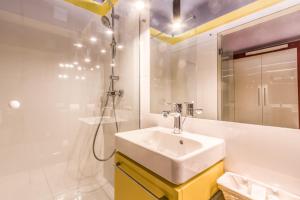 a white bathroom with a sink and a shower at Apartment KOBRO - new city center of Lodz in Łódź