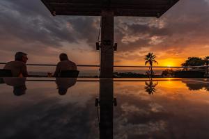 two men sitting in a pool watching the sunset at Ramada Resort Dead Sea in Sowayma