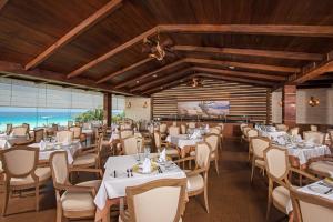 un restaurante con mesas y sillas blancas y una pared de ventanas en Iberostar Selection Cancun, en Cancún
