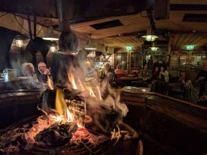 a person cooking food over a fire in a bar at Boat 'Opoe Sientje' in Nijmegen
