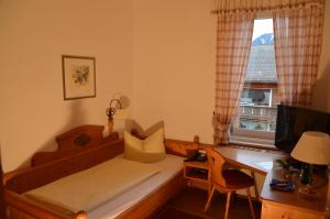 Schlafzimmer mit einem Bett, einem Schreibtisch und einem Fenster in der Unterkunft Gästehaus Maria in Garmisch-Partenkirchen