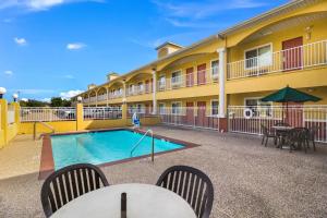 einen Pool vor einem Hotel mit Tischen und Stühlen in der Unterkunft Scottish Inn and Suites Baytown in Baytown