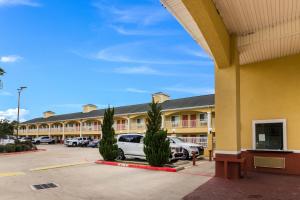 Scottish Inn and Suites Baytown في باي تاون: مبنى كبير به سيارات تقف في موقف للسيارات