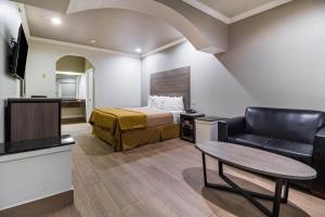 Habitación de hotel con cama, sofá y mesa en Scottish Inn and Suites Baytown, en Baytown