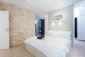 a bedroom with a white bed and a brick wall at Villa Soleil in Vela Luka