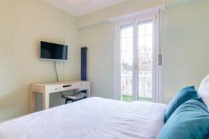 een slaapkamer met een bed en een bureau met een televisie bij Penthouse Jolanda Meran-o in Merano