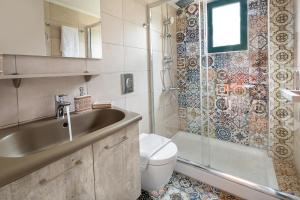 a bathroom with a sink and a toilet and a shower at Villa Apelia - Family Holidays Deals in Vlikhádha