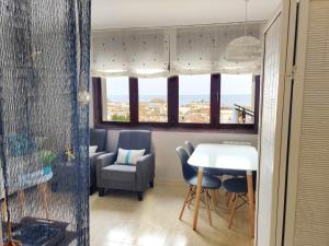 ein Wohnzimmer mit einem Tisch, Stühlen und Fenstern in der Unterkunft Holiday Tossa Apartment in Tossa de Mar