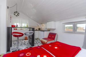 1 dormitorio con cama roja y cocina en Apartments Marin, en Rogoznica