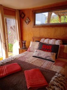 a bedroom with a bed with red pillows and a window at Cabañas Rincon Austral in Puerto Montt