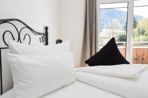 ein Schlafzimmer mit einem Bett mit weißen Kissen und einem Fenster in der Unterkunft Haus Alpenherz in Oberstdorf