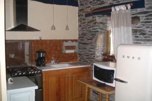 een keuken met een witte koelkast en een stenen muur bij A L'Ombre Du Figuier in Saint-Thois