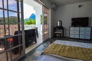 a bedroom with a bed and a television and a balcony at Sugarmon Villas in Soufrière