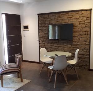 Cette chambre dispose d'une table, de chaises et d'une télévision sur un mur en briques. dans l'établissement monoambiente cerca del centro, à Villa La Angostura
