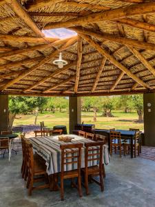 a dining table and chairs under a wooden roof at Ecoposada El Mercedario in Barreal