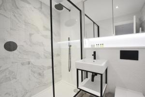 a white bathroom with a sink and a shower at Elysian House - Kensington Serviced Apartments in London