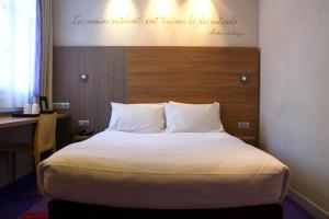 a bed in a hotel room with a desk and a bed at Hôtel de Sévigné in Paris