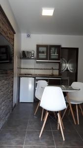 cocina con mesa y 4 sillas blancas en monoambiente cerca del centro en Villa La Angostura