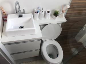 a white bathroom with a sink and a toilet at Ap 408 Beira Mar - Pés na areia in Capão da Canoa +8 photos
