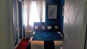 a bedroom with a bed with blue walls and a window at Hotel Lilo near Airport in Tbilisi City