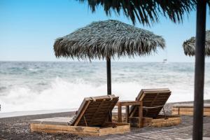 ペリヴォロスにあるBlack Rose Beach Suitesのビーチでの椅子2脚とパラソル1本