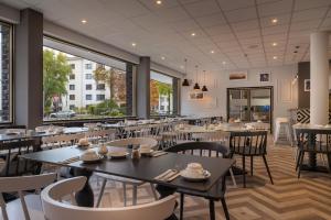 un comedor con mesas, sillas y ventanas en Yggotel Ravn en Berlín