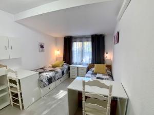 niewielka sypialnia z 2 łóżkami i biurkiem w obiekcie Clubrent - Townhouse La Merced w mieście Calpe