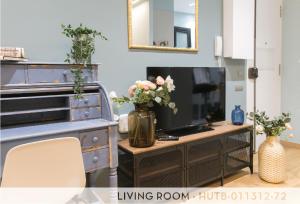 a living room with a television and a vase of flowers at Suite Place Barcelona Còrsega in Barcelona