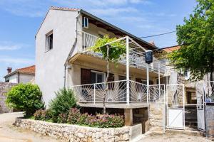 a white house with a balcony and flowers at Guest House Godimento in Čilipi