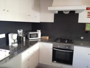 uma cozinha com armários brancos e um micro-ondas branco em Casa Pompona 1 em Rogil
