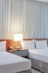 um quarto de hotel com duas camas e uma mesa com um candeeiro em Slaviero Porto Velho em Porto Velho